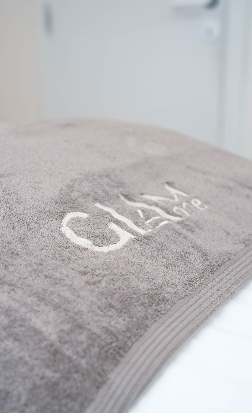 Een opgerolde GLAM ONE handdoek op de behandeltafel