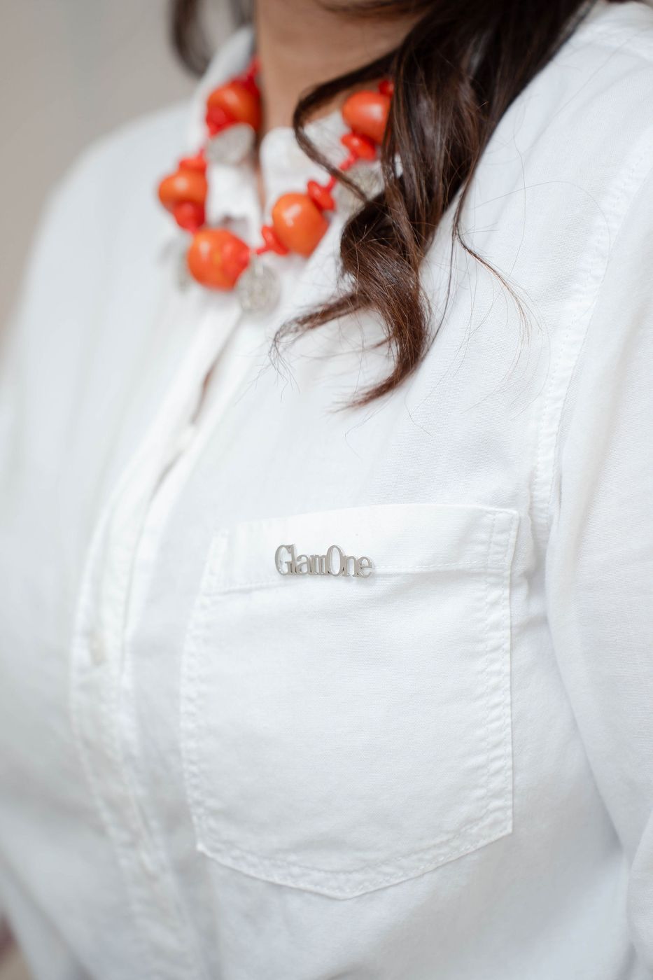 Het GLAM ONE logo geborduurd op T'Lay's witte blouse